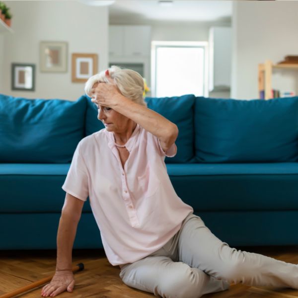 Elderly woman sitting on floor after a fall.